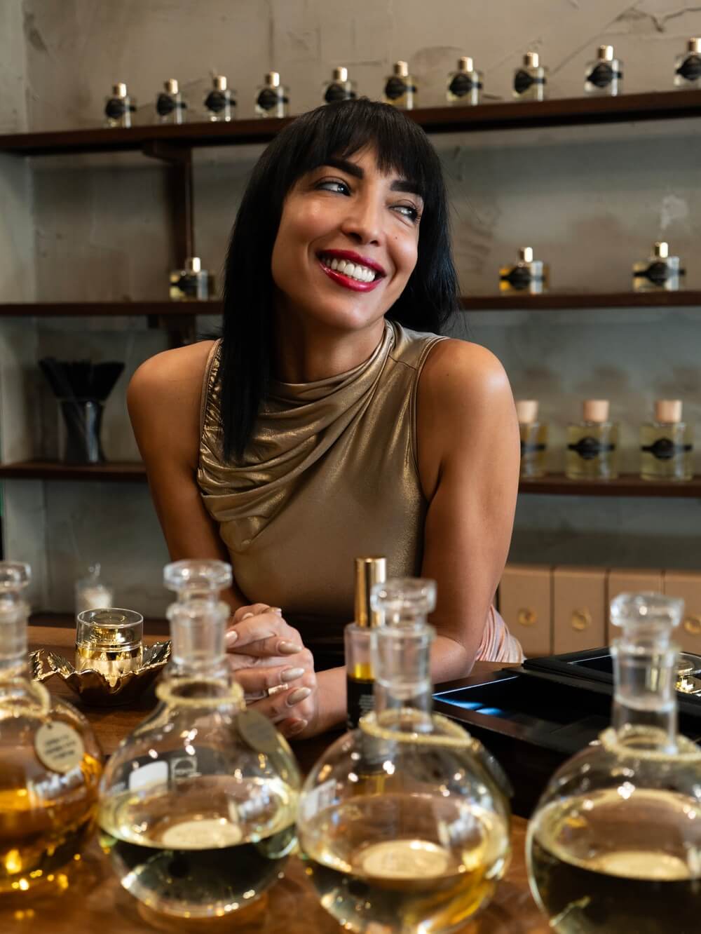 Creatrice di Arabian Prestige sorridente nel suo atelier a Padova, circondata da flaconi di essenze e strumenti per la profumeria artigianale.